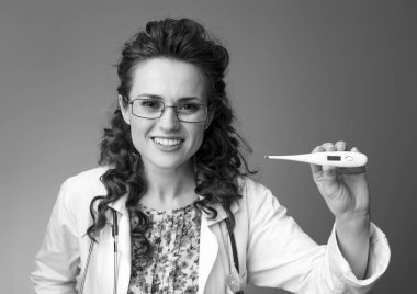 Termometre arka plan karşı gösterilen beyaz tıbbi elbise içinde gülümseyen çocuk doktoru Doktor