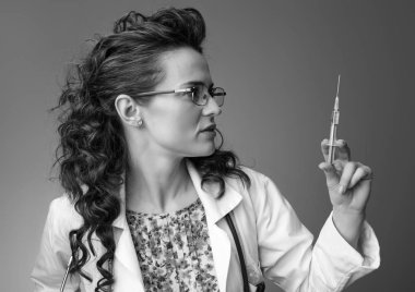 Çocuk doktoru kadın şırınga arka plan bakmak beyaz tıbbi elbise içinde