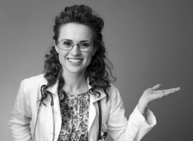 bir şey üzerinde arka izole boş Palm'da sunan beyaz tıbbi elbise içinde gülümseyen pediatrist doktor