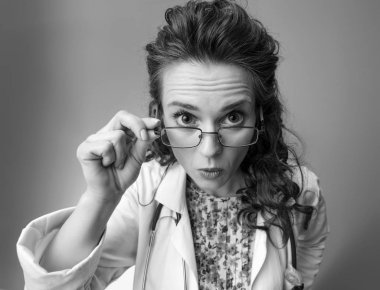 Kamera arka plan üzerinde izole beyaz tıbbi elbise arıyor sürpriz çocuk doktoru Doktor portresi