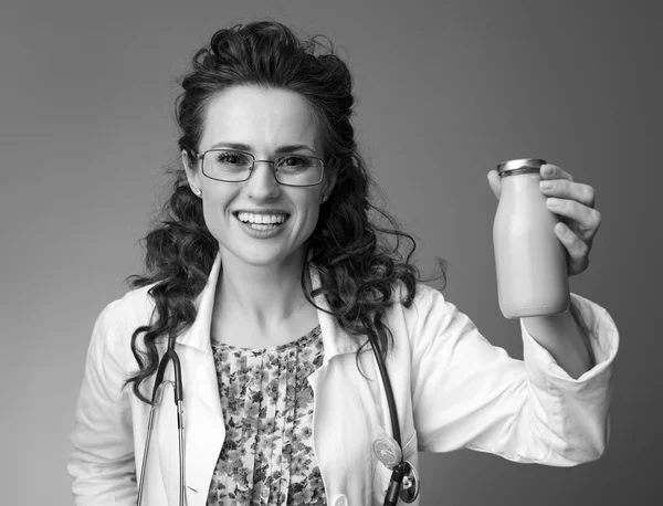 微笑的儿科医生妇女在白色的医疗长袍一瓶喝酸奶隔离 — 图库照片