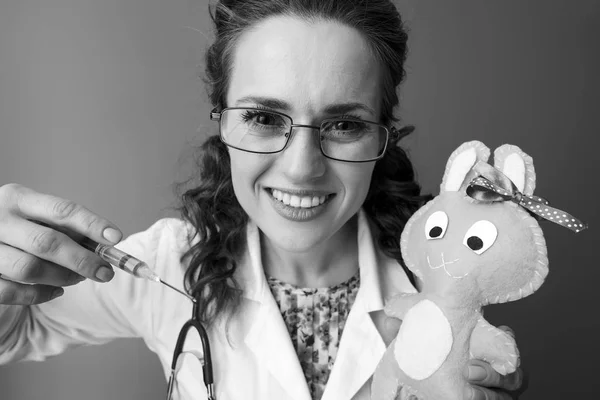 Uśmiechnięta Kobieta Pediatra Białą Szatę Medycznych Gospodarstwa Zabawka Pomocą Strzykawki — Zdjęcie stockowe