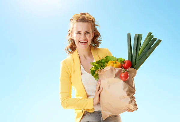 하늘에 식료품 가방와 노란색 재킷을 여자의 초상화 — 스톡 사진