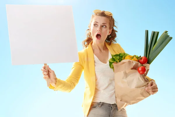 Überraschte Moderne Frau Gelber Jacke Mit Papiertüte Mit Lebensmitteln Und — Stockfoto