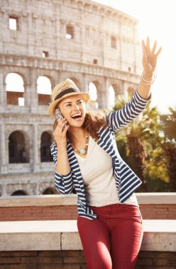 bir cep telefonu ve handwaving konuşan Colosseum yakınındaki hasır şapkalı mutlu şık kadın