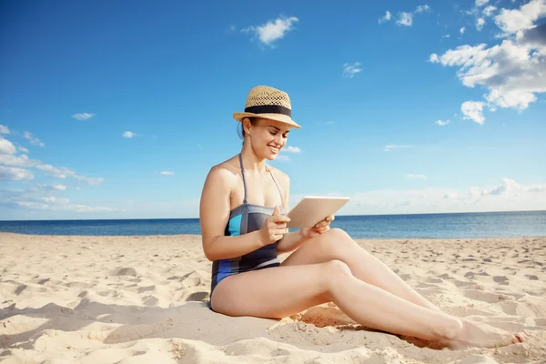 快乐的年轻女子在海滩海滩上使用平板电脑 — 图库照片