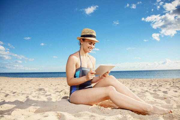 happy young woman in beachwear on the beach using tablet PC