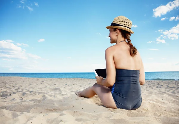 タブレット 浜辺で水着で若い女性の後ろから見てください — ストック写真