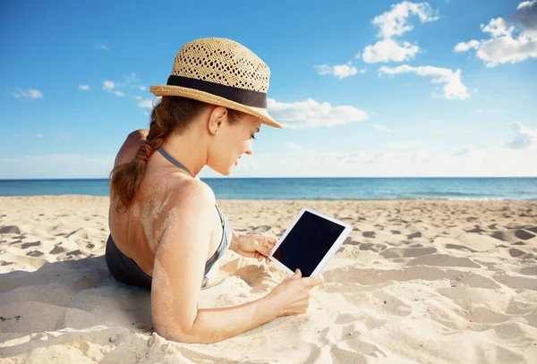从后面看到的年轻女子泳装在海滩上使用 Tablet — 图库照片