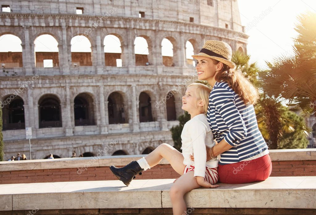happy mother and child travellers in the front of Colosseum looking into the distance