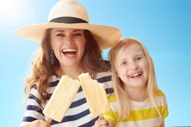 mutlu genç anne ve çocuk dondurma mavi gökyüzü karşı bir sopa ile