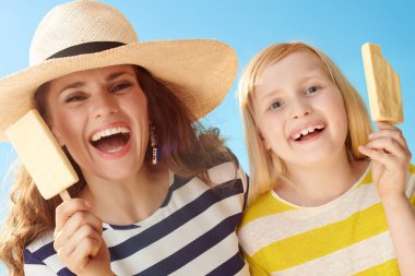 mutlu genç anne ve çocuk dondurma mavi gökyüzü karşı bir sopa ile