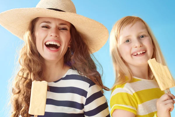 微笑现代母亲和女儿用冰淇淋对蓝天的棍子 — 图库照片