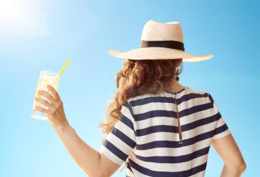 Kokteyl serinletici ile mavi gökyüzü karşı hasır şapkalı şık kadın arkasından gördüm