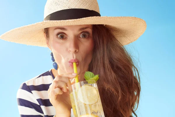 滑稽时髦的妇女在草帽反对蓝色天空喝提神鸡尾酒 — 图库照片