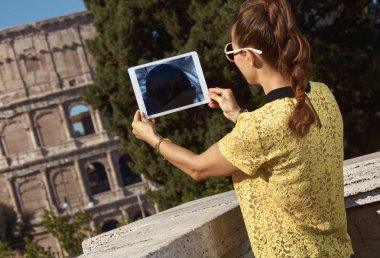sarı bluz tablet Pc yakınlarında Kolezyum, Roma, İtalya ile fotoğraf çekmek kadında genç Gezgin görünümünü geri