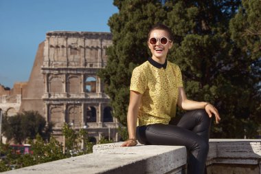 sarı bluz parapet yakınlarında Kolezyum, Roma, İtalya, otururken mesafe içine bakarak mutlu trendy turist kadın