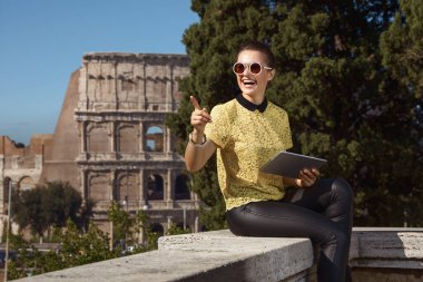 sarı bluz ile mutlu trendy turist kadın tablet Pc bir kenara Colosseum, Roma, İtalya, işaret