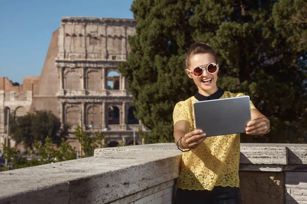 smiling modern tourist woman in yellow blouse taking selfie with tablet PC near Colosseum , Rome, Italy