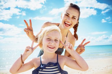 mutlu modern anne ve çocuk kumsalda zafer jest gösterilen beachwear