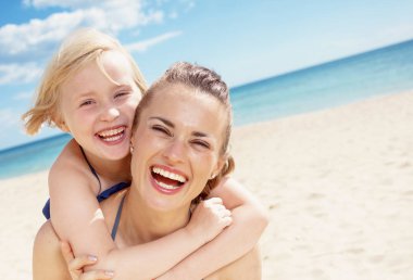 Mutlu modern anne ve çocuk gülüyor ve sahil üzerinde sarılma mayo içinde portresi