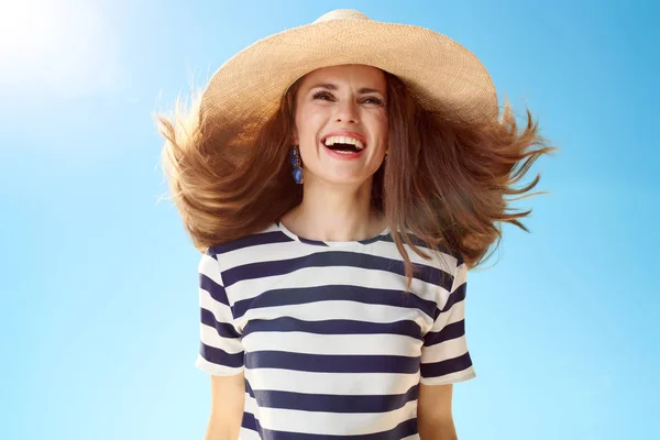 青空になびく髪と麦わら帽子の若い女性を笑顔 — ストック写真