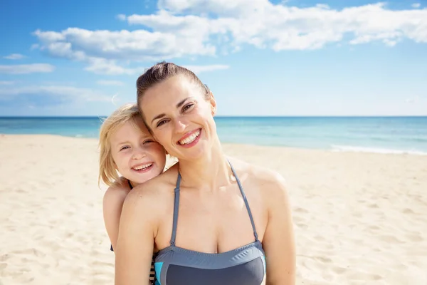 微笑的年轻母亲和女儿的肖像在海滩看在海岸上的相机 — 图库照片