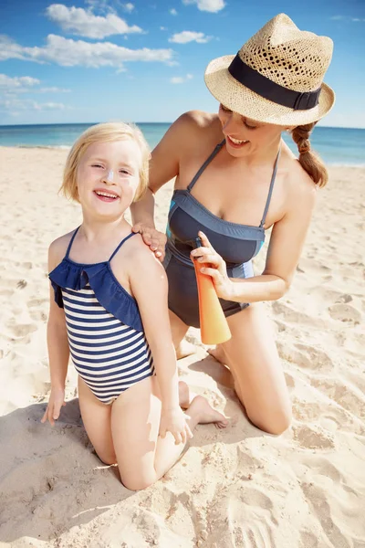 快乐的现代母亲和女儿泳装应用晒黑化妆水海岸 — 图库照片