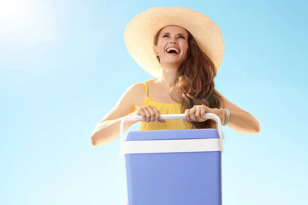 青い空に探しているプラスチックのクーラー ボックスと麦藁帽子で幸せなフィット女 — ストック写真