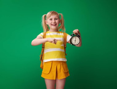 çalar saat yeşil zemin üzerine işaret sırt çantası ile öğrenci gülümseyen