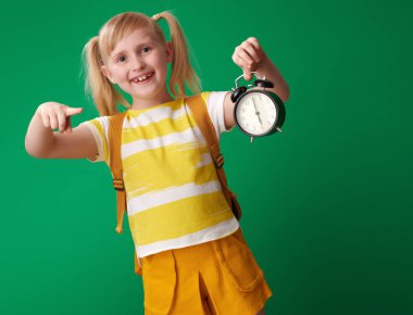 çalar saat yeşil zemin üzerine işaret sırt çantası ile mutlu öğrenci