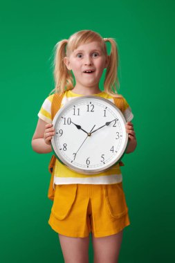 Saat yeşil arka plan üzerinde gösterilen sırt çantası ile sürpriz okul kız