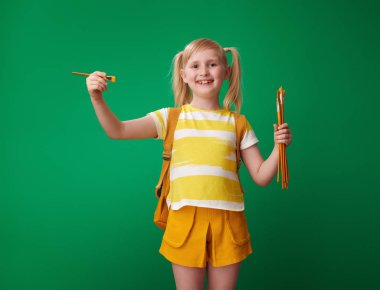 Hava Fırçası ile yeşil arka plan üzerinde çizim sırt çantası ile gülümseyen liseli kız 