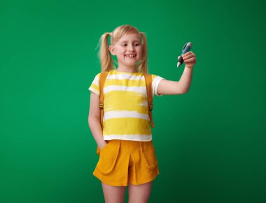 yeşil bir arka plana dayanır havada büyük kalemiyle yazma sırt çantası ile öğrenci gülümseyen