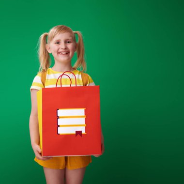 ileti örneği ve kameraya yeşil arka plan üzerinde seyir ile alışveriş çantası elinde sırt çantası ile gülümseyen liseli kız