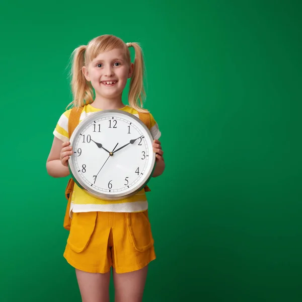 Sonriente Chica Escuela Con Mochila Mostrando Reloj Contra Fondo Verde —  Fotos de Stock