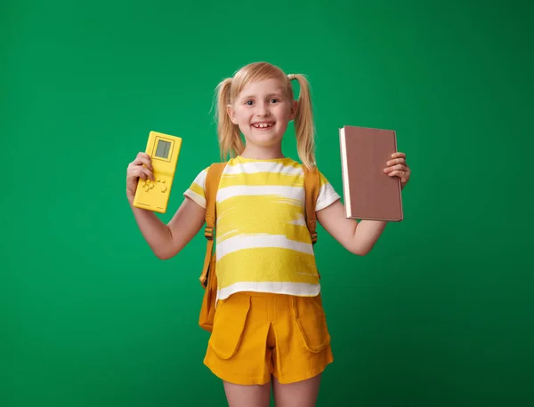 Glückliches Schulmädchen Mit Rucksack Mit Videospiel Und Buch Auf Grünem — Stockfoto