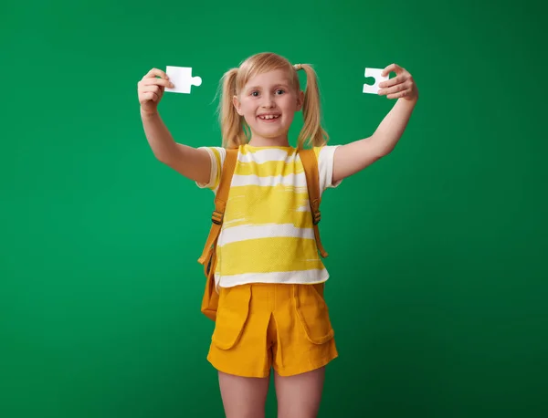 Lächelndes Schulmädchen Mit Rucksack Mit Puzzleteilen Auf Grünem Hintergrund — Stockfoto