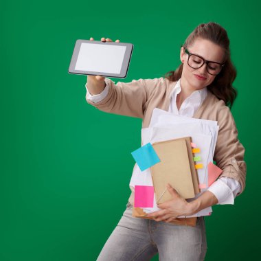 üzgün modern öğrenci kadın kitap ve notlar kayıtlarla ve tablet Pc gösteren yeşil zemin üzerine teknolojinin kolaylığı ile