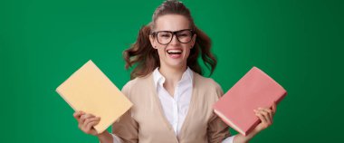 genç öğrenci kadın bardaklarda ise kitap tutan ve yeşil arka plan üzerinde poz gülüyor