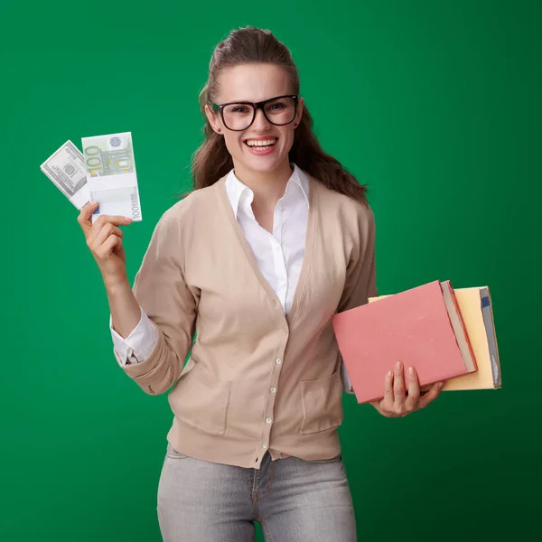 快乐的年轻学生妇女与书和金钱包装在绿色背景 — 图库照片