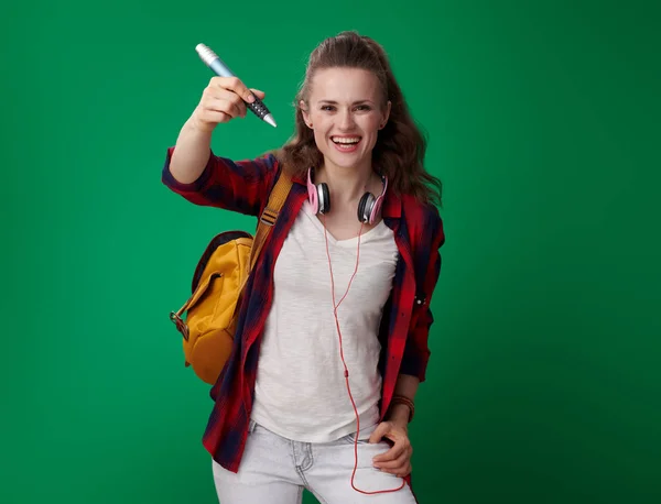 バックパックと緑の背景に大きなペンで書いて空気でヘッドフォンの魅力的な学生女性 — ストック写真
