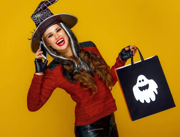 Sorrindo Jovem Mulher Traje Bruxa Segurando Saco Compras Halloween Falando — Fotografia de Stock