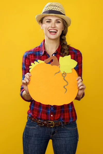 黄色の背景で健康食品のコンセプトに装飾的なカボチャを示す市松模様のシャツで現代の女性生産者の笑顔 — ストック写真