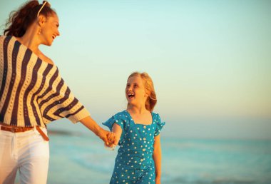 mutlu modern anne ve kızı deniz kıyısı üzerinde günbatımında yürüyüş 