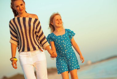 Modern anne ve çocuk akşam sahil üzerinde yürüme gülümseyen 