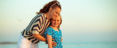 mutlu modern anne ve çocuk kumsalda gün batımında sarılma 