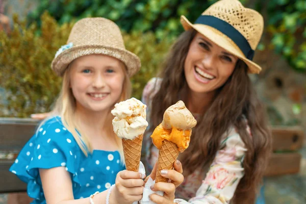 快乐的年轻母女旅行者坐在替补席上 在意大利皮恩扎街头的镜头前展示冰淇淋 — 图库照片