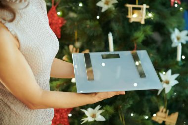 Noel ağacı ağırlık tutarak yakın genç ev hanımı ölçekler