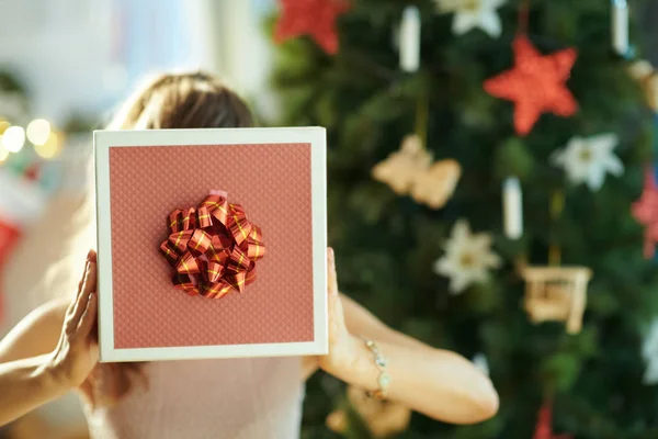 Ung Kvinna Nära Julgran Håller Jul Nuvarande Låda Framför Ansiktet — Stockfoto